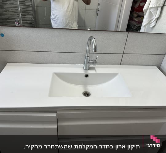 כיור אמבטיה עם ברז מותקן על ארון לבן